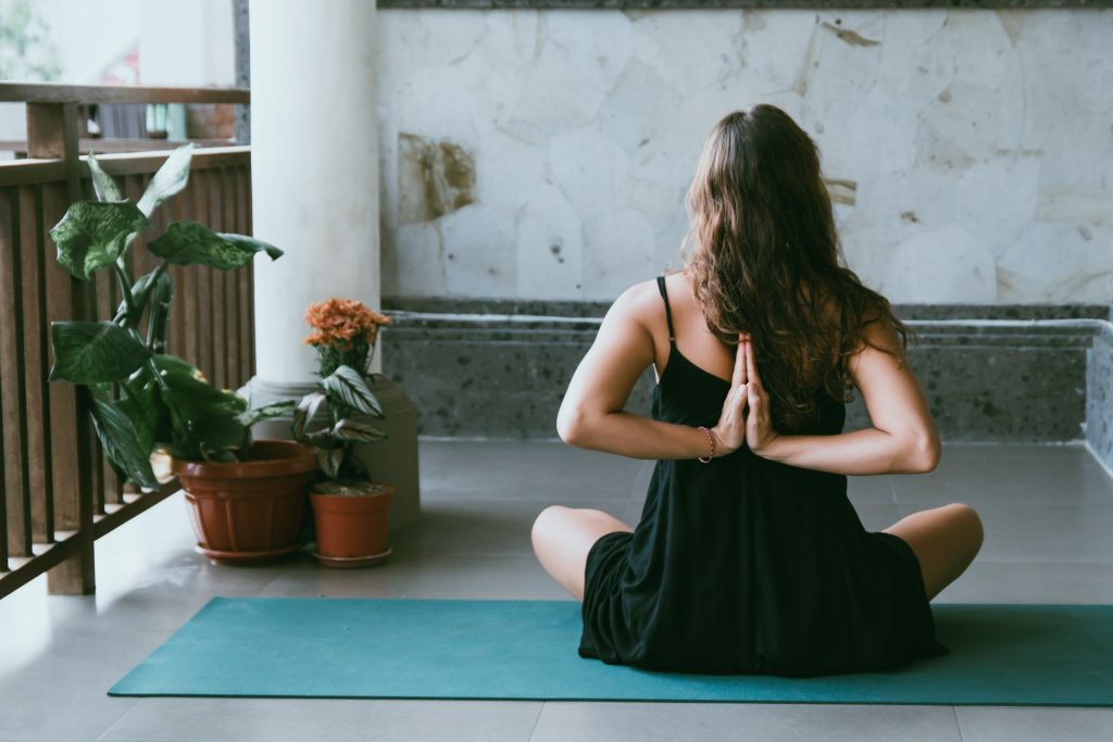 Ragazza di spalle sul balcone in posizione yoga