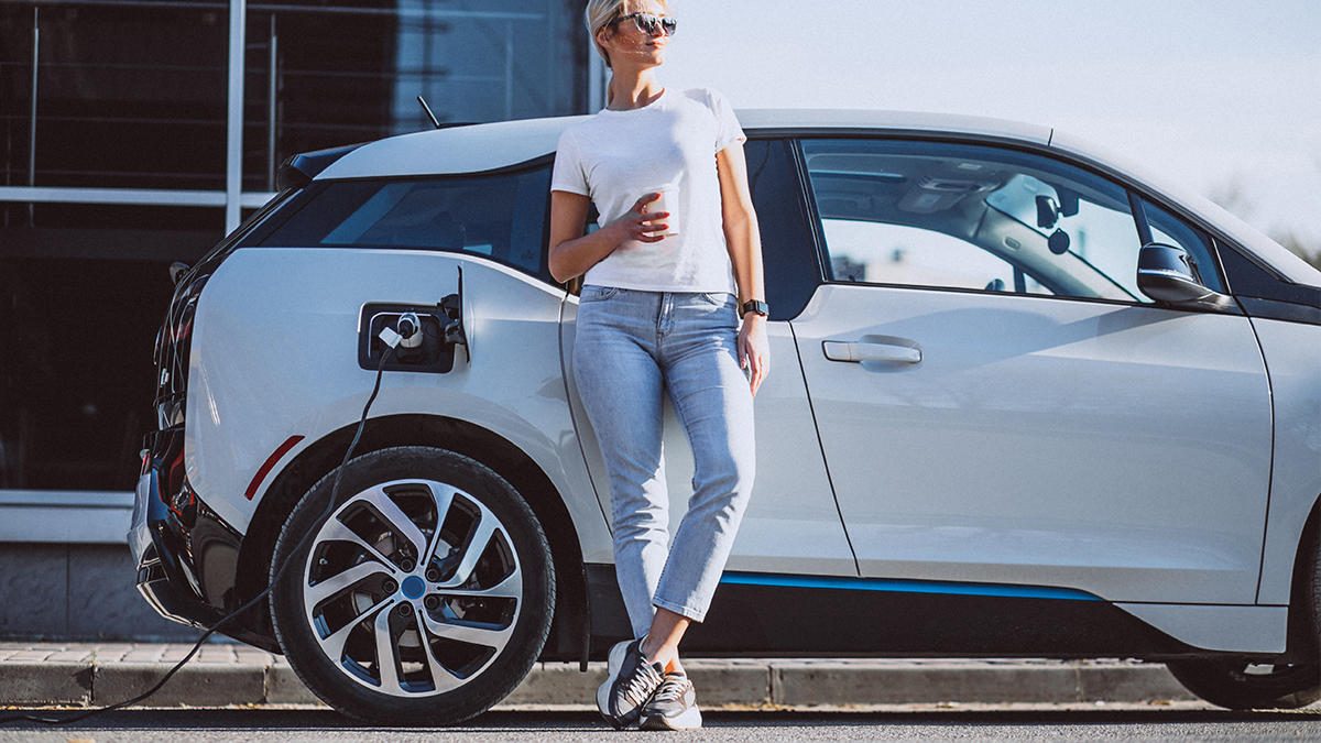 auto elettrica in carica con donna che attende