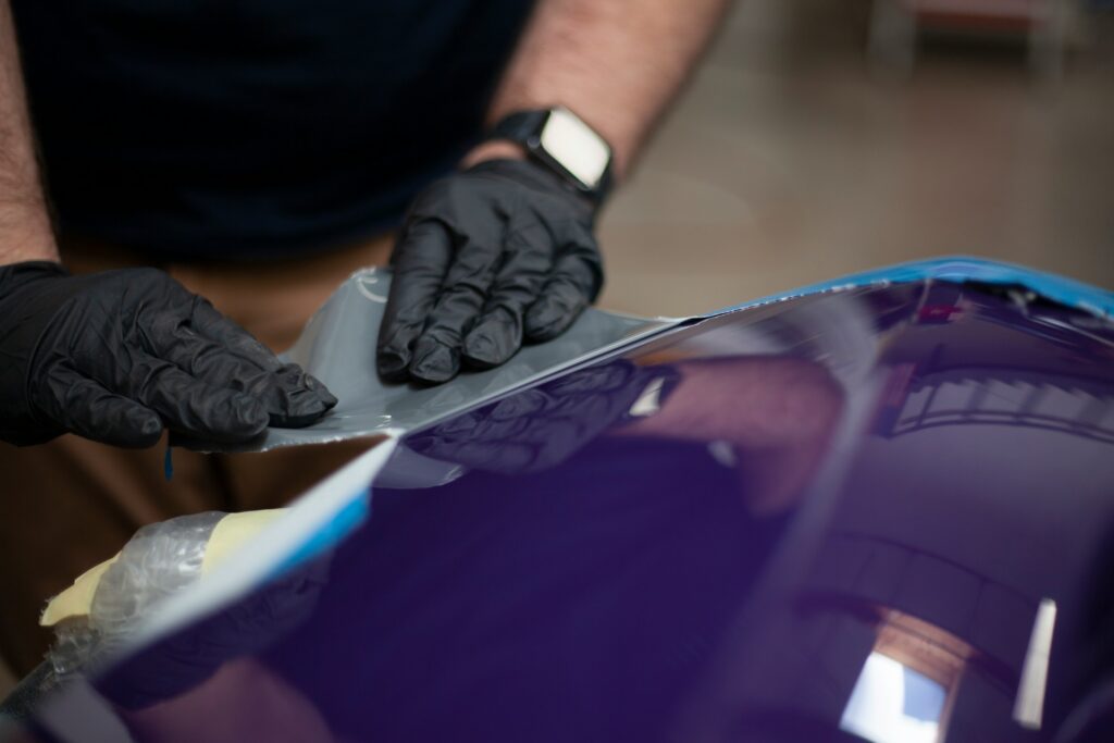 lavoro di car wrapping su auto: dettaglio mani con guanti neri