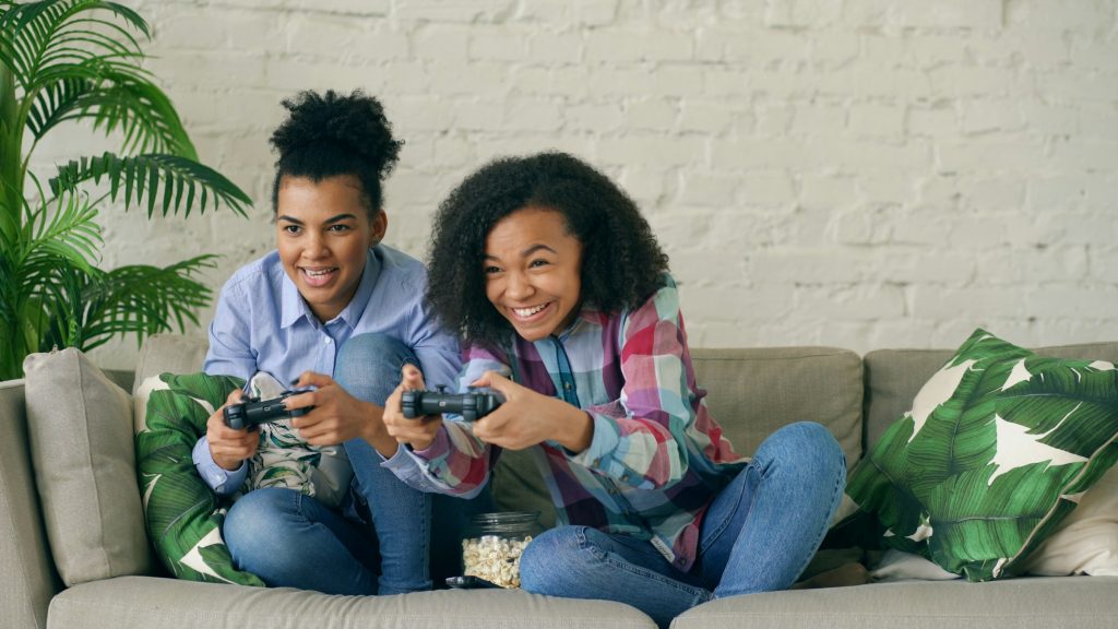 due ragazze giocano alla playstation sul divano