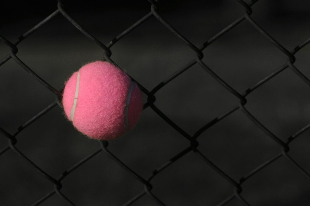 Pallina da tennis rosa su rete nera