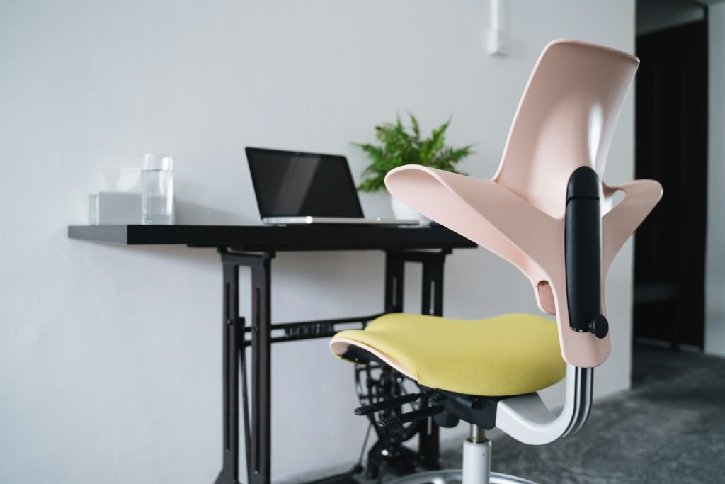 Sedie ergonomica rosa e verde vicina a desktop con laptop