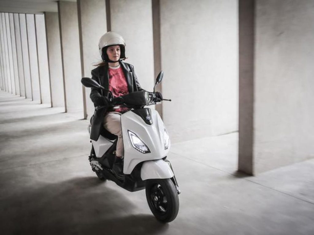 ragazza su scooter Piaggio bianco con casco